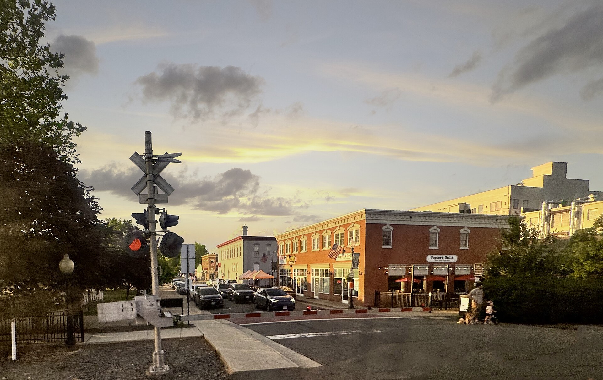 A railroad crossing and brick storefronts in downtown Manassas at sunset